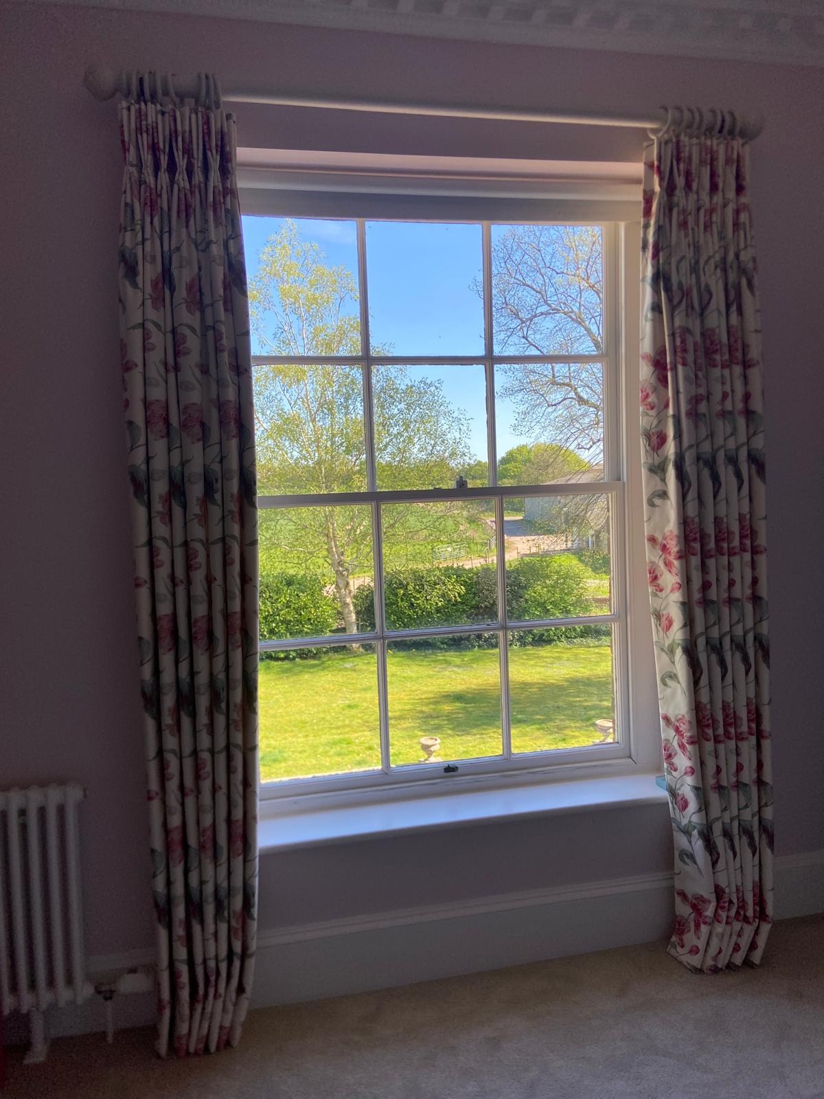 Pink tulip pinch pleat curtains at a sash window