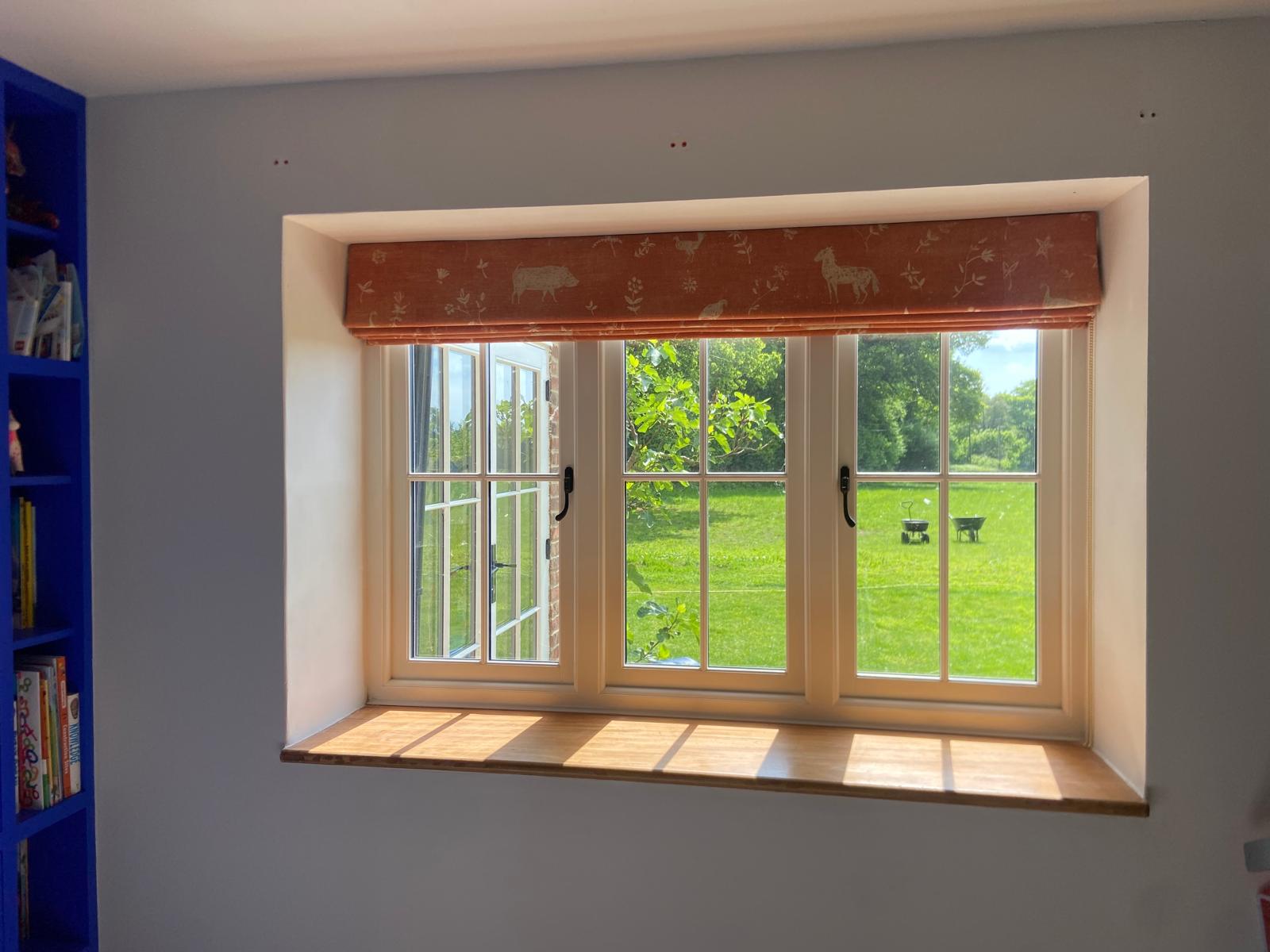 Terracotta farmyard print Roman blind in a deep window recess