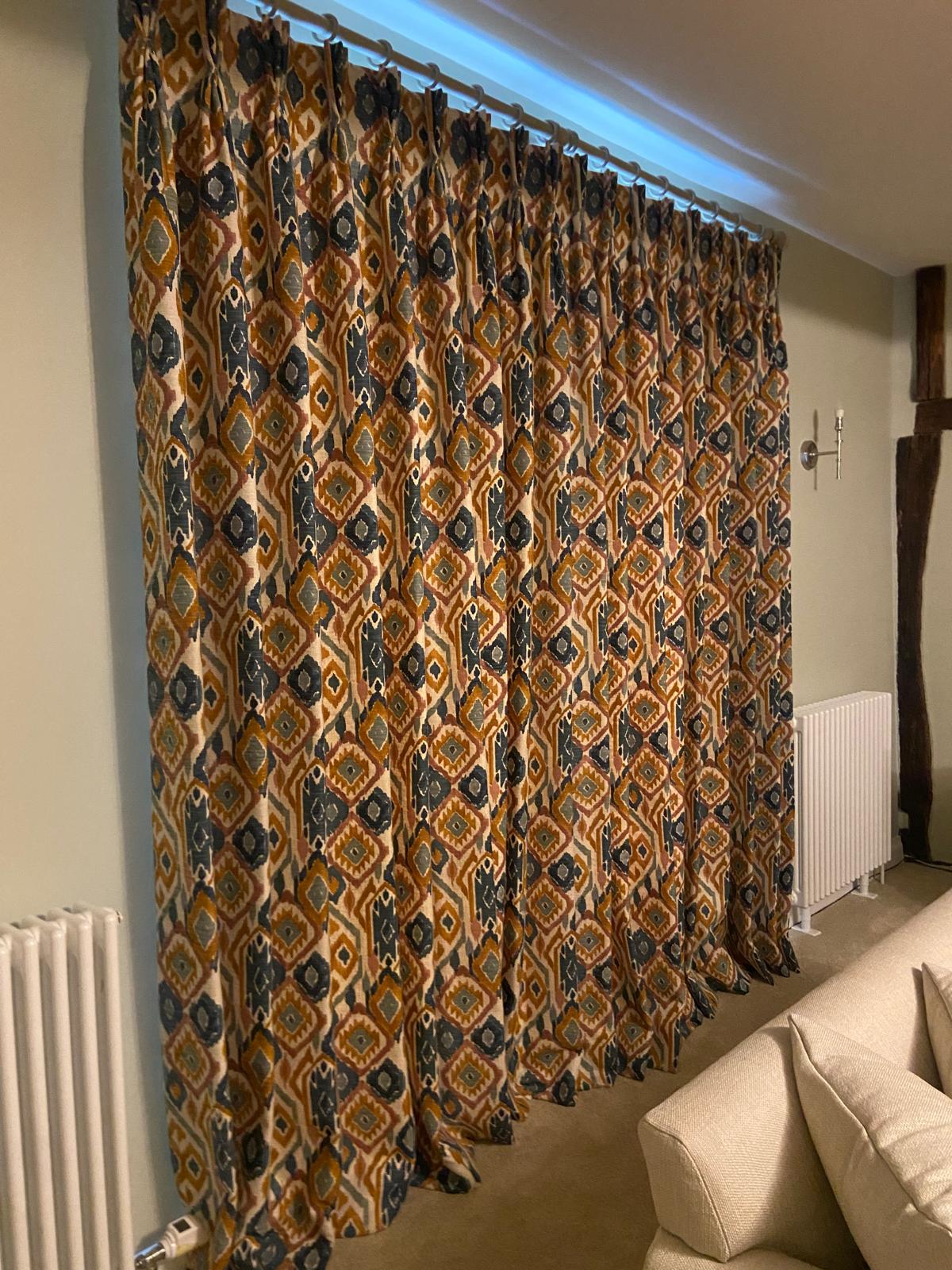 Ikat-pattern pinch pleat curtains in a beamed sitting room