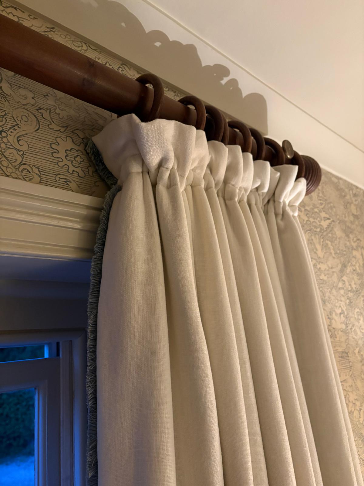 Cream linen curtains with fringe trim on a wooden pole