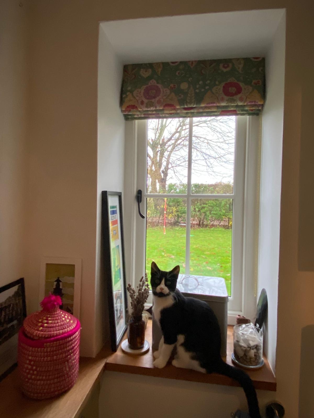 Folk-print Roman blind in a cottage window recess