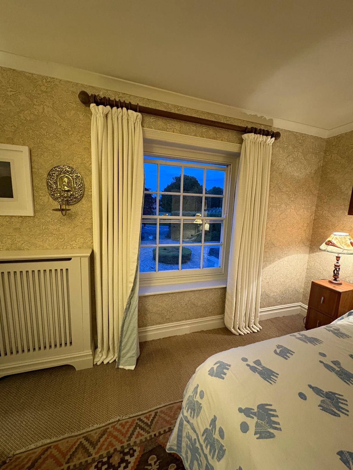 Cream interlined curtains on a wooden pole in a bedroom