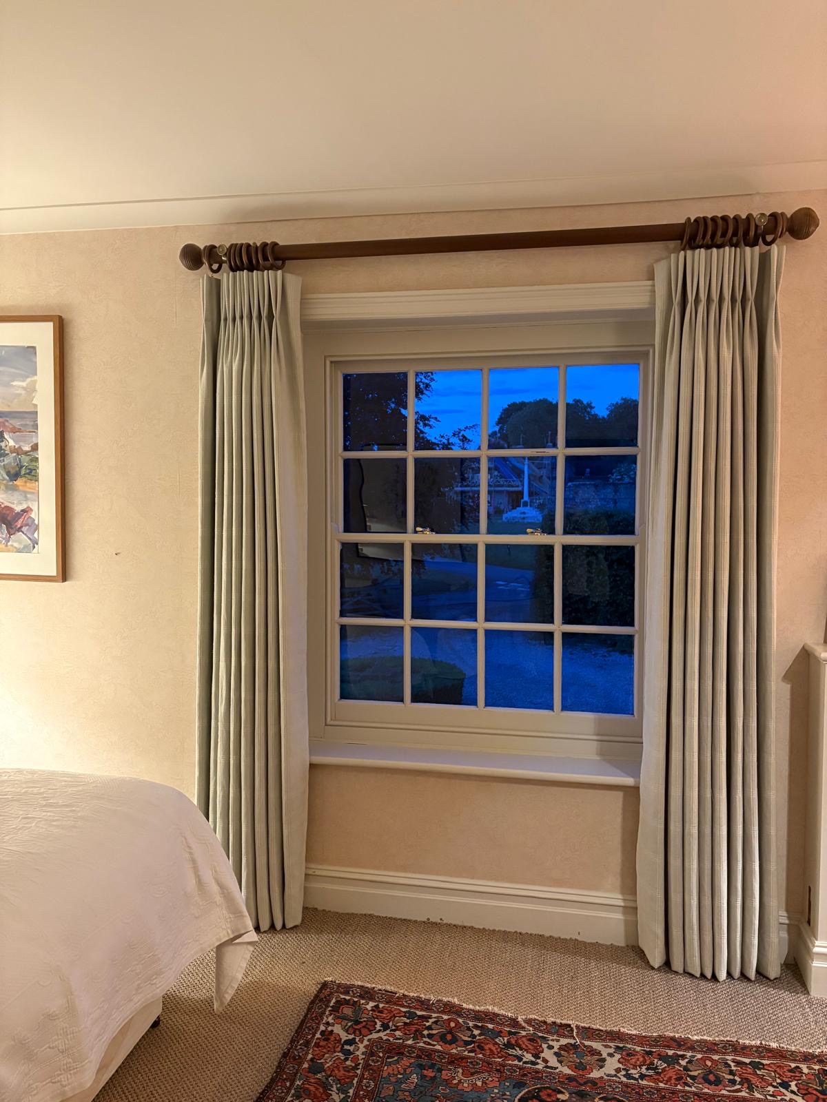 Triple-pleat checked curtains on a stained wood pole