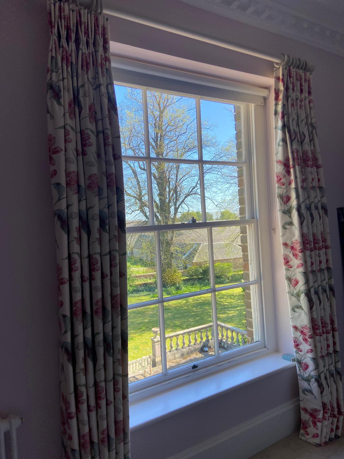 Pink tulip floral pinch pleat curtains at a sash window