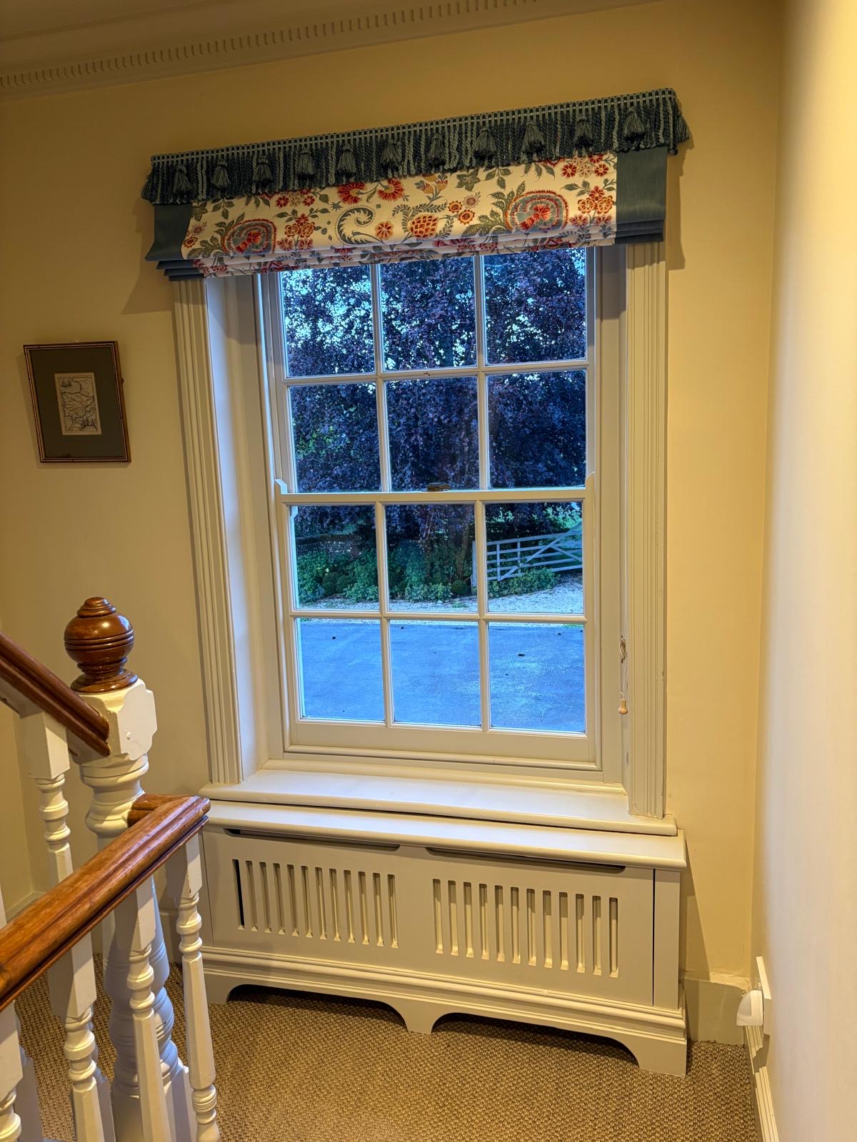 Tassel-trimmed pelmet with floral Roman blind on a staircase window